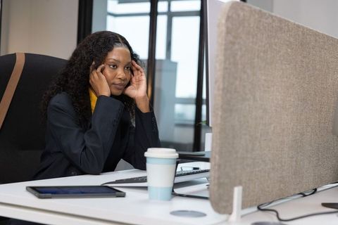 African american professional rubbing temples at desk in modern office workstation