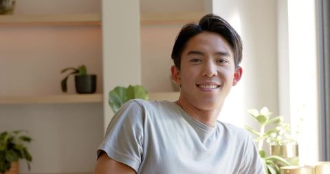 Smiling Asian Man Relaxing at Home with Minimalist Decor