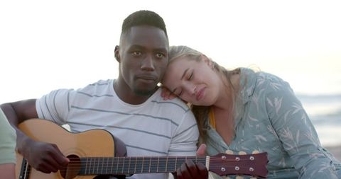 Young couple enjoying beachside guitar melodies at sunset