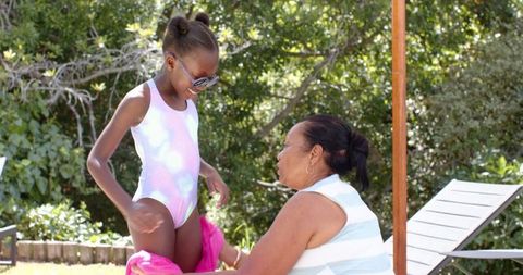 Grandmother Wrapping Towel Around Granddaughter at Poolside