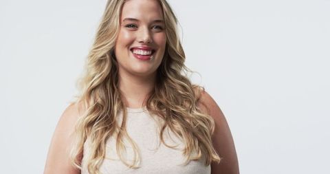 Confident Plus Size Woman Smiling in Studio with Long Blonde Hair