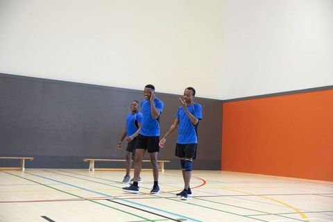 African american male athletes walking on indoor gym court in blue uniforms, team practice