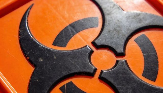 Macro biohazard trefoil on scratched orange container lid safety warning sign close-up