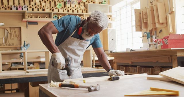 African american male carpenter drilling holes in wooden plank using hand drilling machine. carpentry, craftsmanship and handwork concept