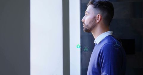 Professional Man Observing Sustainable Energy Symbols at Work