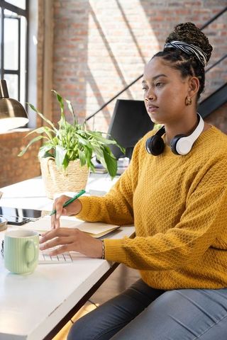 Focused Woman Working at Loft Office Desk with Coffee and Laptop