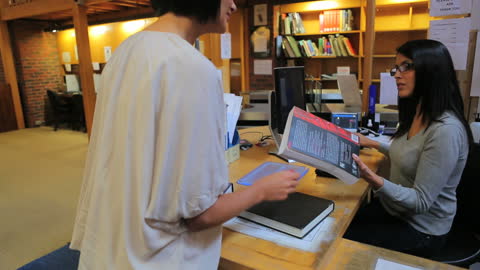 Librarian Assisting Patron at Library Checkout Counter
