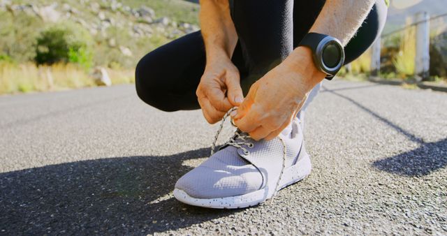 Caucasian woman tying her shoe outdoors, with copy space. She's preparing for a run on a sunny day, highlighting a healthy lifestyle.