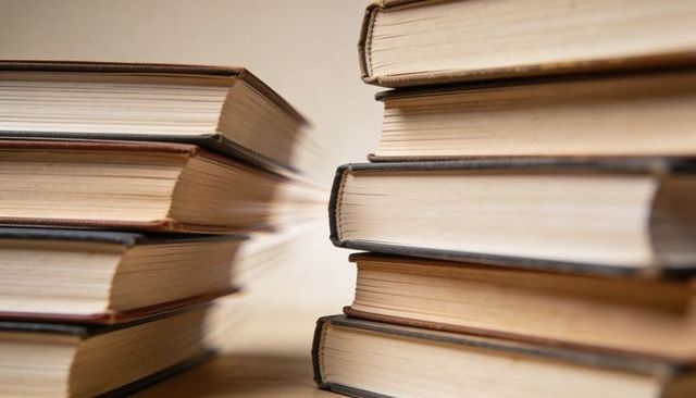 Vintage hardcover book stacks forming narrow gap with textured page edges and warm patina