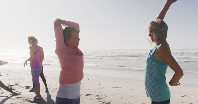 Senior women stretching and exercising on the beach at sunrise portrays active living and a healthy lifestyle. This image is ideal for health and fitness promotions, exercise programs for older adults, wellness campaigns targeting seniors, and illustrating the importance of outdoor activities for maintaining good health.