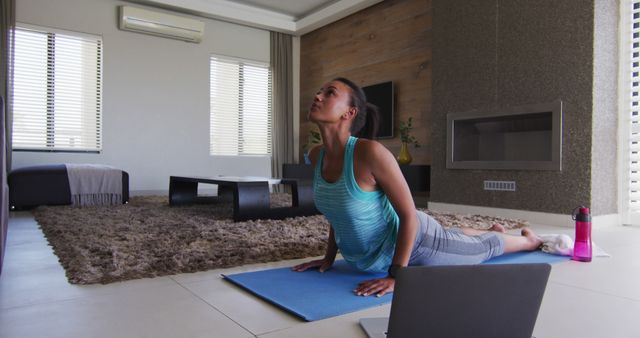 African American woman practicing yoga exercise on mat indoors. Ideal for promoting healthy lifestyle, indoor fitness routines, yoga classes, mental well-being, and home exercise programmes.