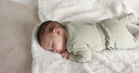 Sleeping infant on plush white blanket in nursery setting