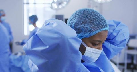 Female surgeon adjusting surgical cap and mask in operating room preparing for procedure
