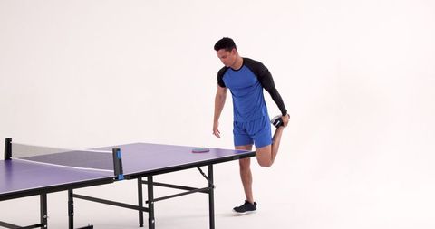 Athlete Stretching Beside Ping Pong Table in Studio Setting