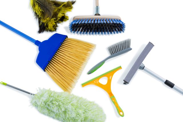 High angle view of various cleaning tools including broom, brush, duster, and squeegee on white background. Ideal for use in articles, advertisements, and guides related to household cleaning, hygiene, and maintenance. Perfect for illustrating cleaning tips, product reviews, and home organization content.