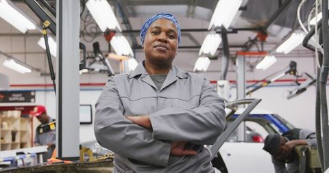 Confident Female Mechanic in Workshop Crossing Arms