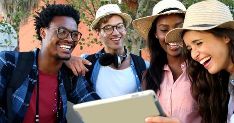 Diverse Friends Laughing Together Outdoors with Tablet