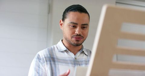 Young man reading document at minimalist workstation with natural light and focus