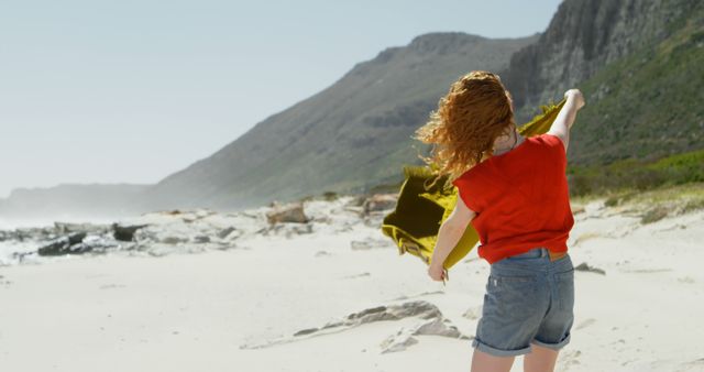 Woman Enjoying Windy Day on Sandy Coast with Majestic Mountain Backdrop - Download Free Stock Images Pikwizard.com