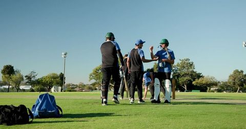 Multicultural cricket team entering pitch preparing batting practice celebrating teamwork