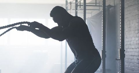 Man Exercising with Battle Ropes in Gym for Strength