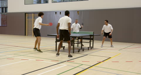 Group of Men Engaged in Competitive Table Tennis Match in Gym