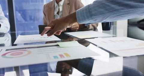 Pointing at Financial Charts on Glossy Conference Table During Team Data Review