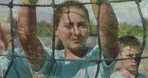 Youth Athletics Team Standing Behind Net on Sunny Field