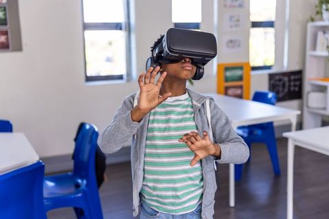 African american schoolboy exploring virtual reality in classroom with vr headset