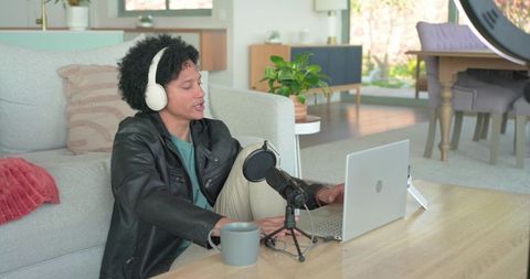 Young man podcasting from home with laptop, microphone, headphones and ring light