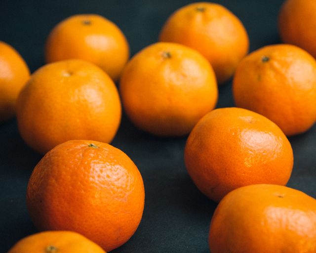 Vividly colored mandarin oranges attract attention with their fresh look against a dark background. Ideal for use in articles and posts about healthy eating, nutrition, and vitamin C sources. Can also be used for grocery promotions, juice advertisements, and food blogs highlighting fresh produce.