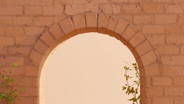 Sunlit terracotta archway framing pale plaster courtyard with climbing vines