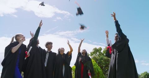 Celebrating Diverse Graduates Tossing Caps on Sunny Campus Lawn Holding Diplomas