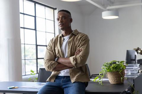 Young Professional Leaning on Desk in Modern Workspace