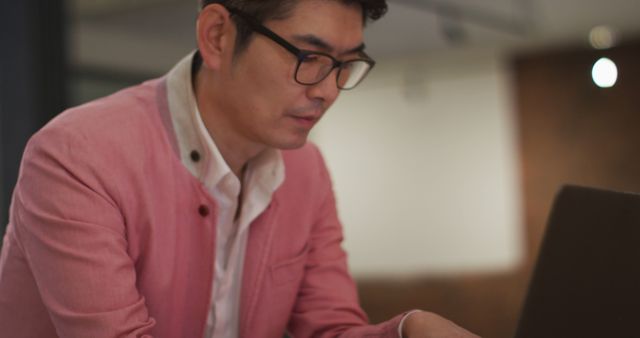 Smartly dressed asian businessman sitting at desk using laptop wondering - Download Free Stock Photos Pikwizard.com