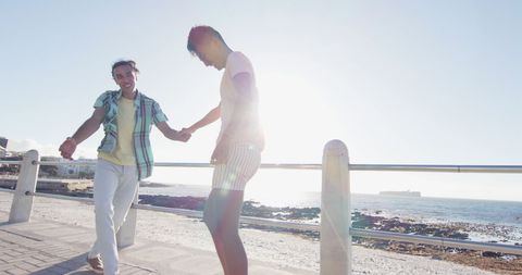 Happy Interracial Gay Couple Walking Along Seaside Promenade