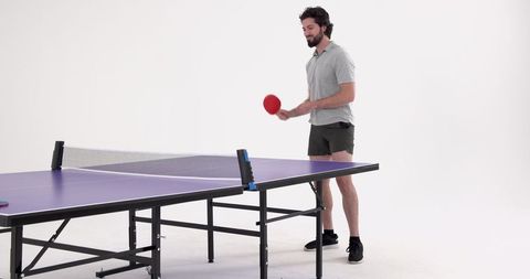 Man preparing for table tennis serve on purple ping pong table