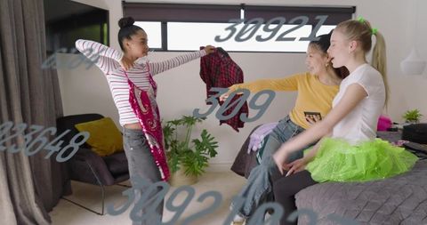 Teen girls trying sparkly dresses and tutu during lively bedroom styling with smartphone