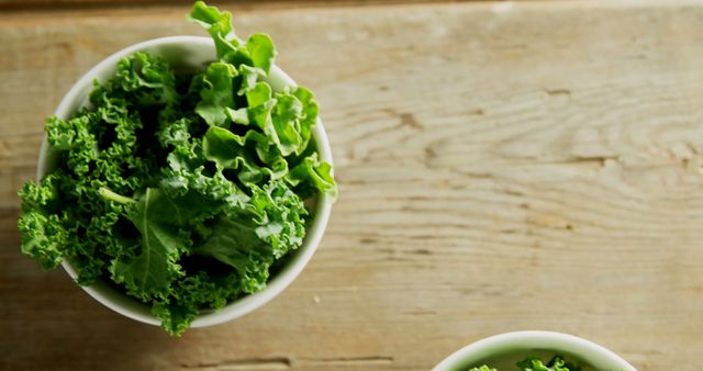 Close up of white bowl with green fresh lettuce on wooden table, copy space. Health, diet and food.
