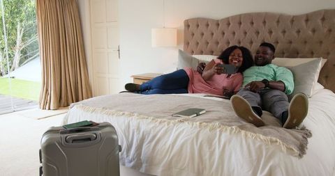 Couple Relaxing and Bonding on Bed While Browsing Smartphone