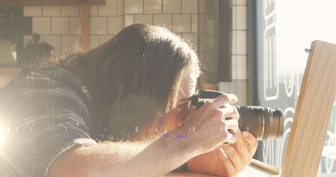 Photographer Taking Creative Shot in Sunlit Cafe