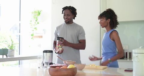 African American Couple Preparing Healthy Fruit Smoothie at Sunlit Modern Kitchen Island