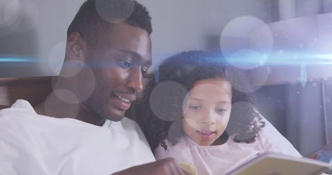 Father Reading Storybook to Daughter Under Fairy Lights