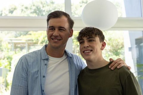 Father and teen son smiling in bright modern home with garden view and soft natural light
