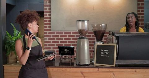 African american baristas taking orders, pulling espresso behind brick cafe counter