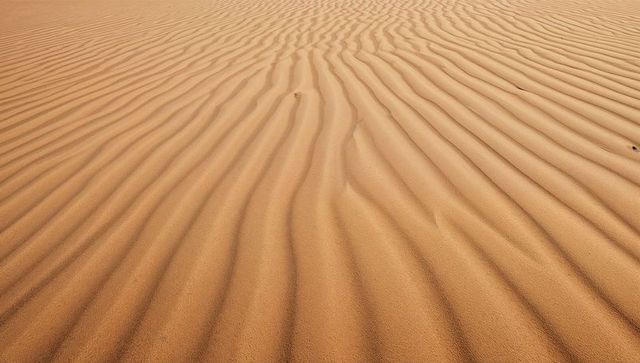 Golden desert sand ripples forming parallel dune ridges and textured patterns
