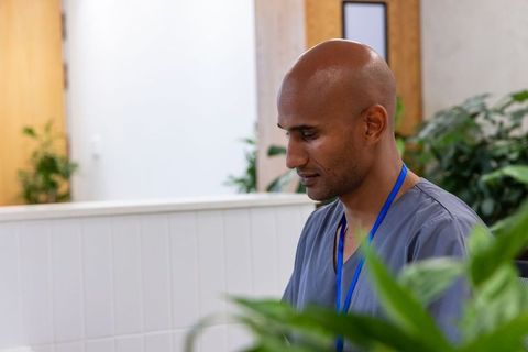 African american healthcare worker at clinic reception wearing blue lanyard and scrubs