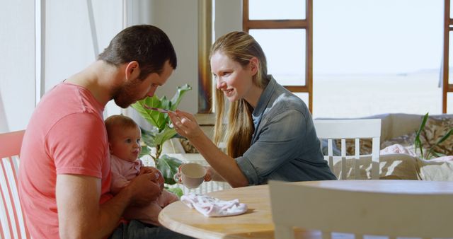 Happy Young Family Feeding Baby at Breakfast Table - Download Free Stock Images Pikwizard.com