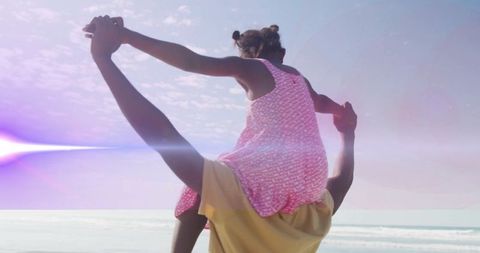 Father Lifting Daughter on Shoulders Under Sunlit Beach Sky