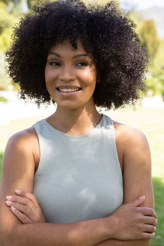 Smiling African American Woman with Curly Hair in Sunlit Park